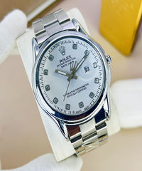 Silver watch with a white face on a beige surface, featuring the brand logo.