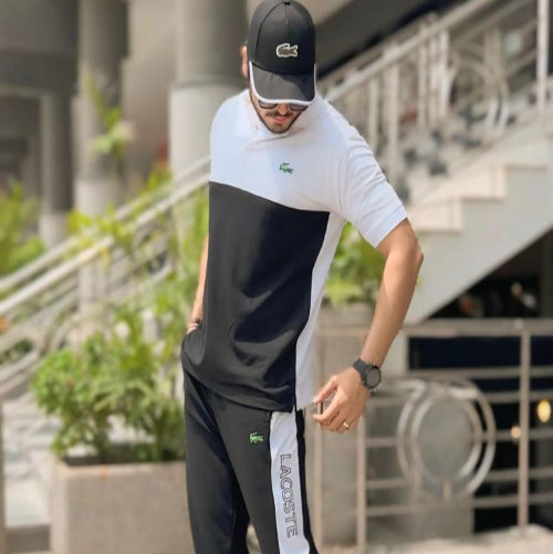 Man wearing a black and white outfit with a cap, standing outdoors.