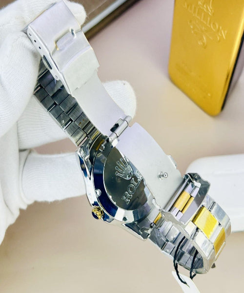 Rolex watch with transparent case back on a beige surface, with a gold box in the background.