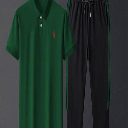 Green polo shirt and black pants on hangers against a dark background