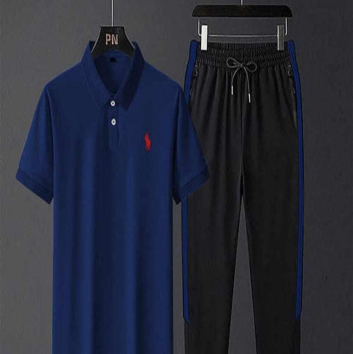 Blue polo shirt with red logo and black pants on hangers against a dark background