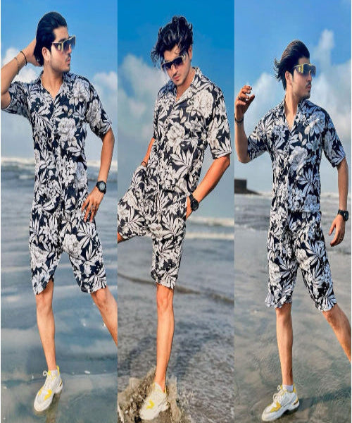 Man in a floral outfit standing on a beach with ocean waves in the background