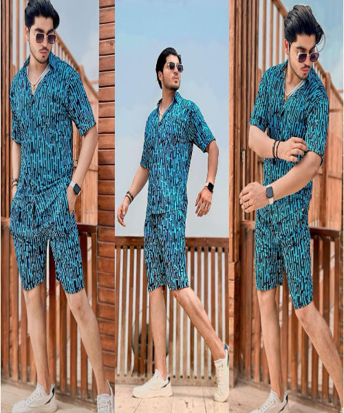 Man wearing a blue patterned outfit standing on a wooden deck with a clear sky background.