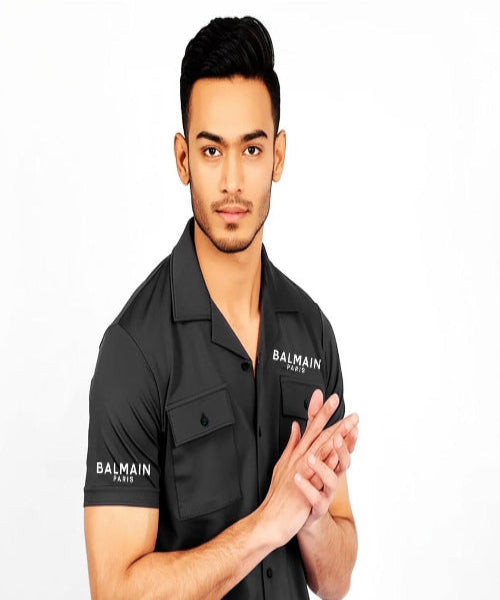 Man wearing a black Balmain shirt on a white background