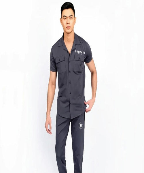 Man wearing a dark gray outfit with brand logos on a white background