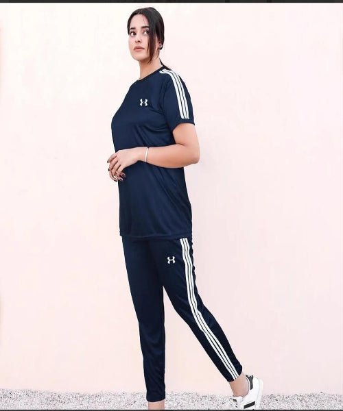 Person wearing a navy Under Armour outfit with white stripes on a light pink background