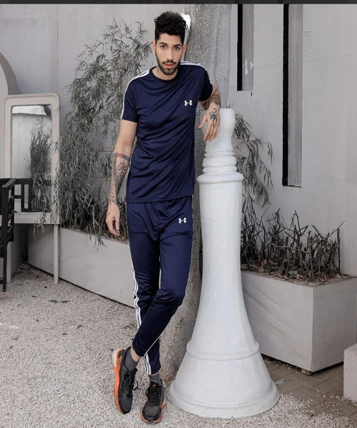 Man wearing a navy Under Armour outfit standing next to a decorative column outdoors.